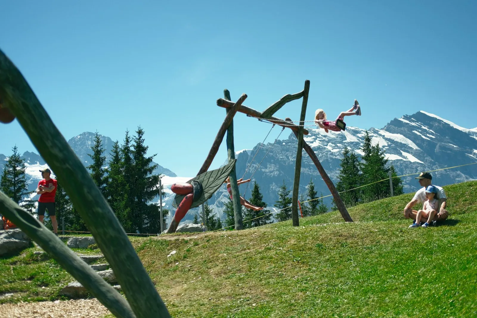 Kinder auf einer Schaukel vor Bergkulisse